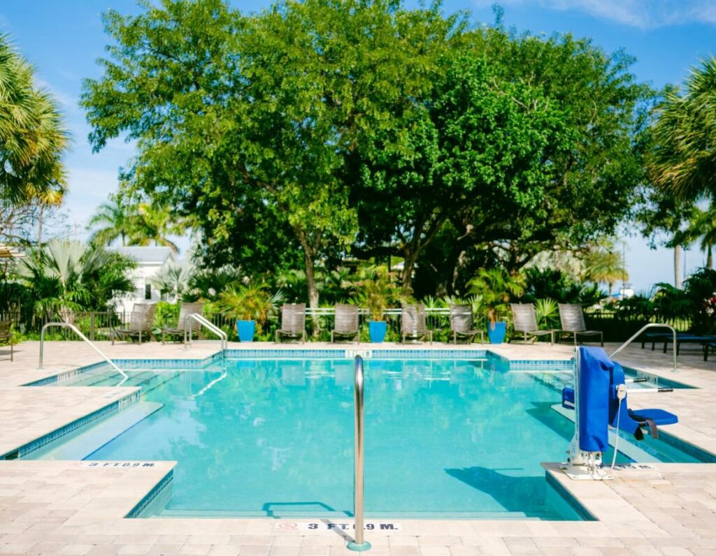 a great teal pool offset by the brightness of the green trees behind it featured at one of the best resorts in the Florida Keys
