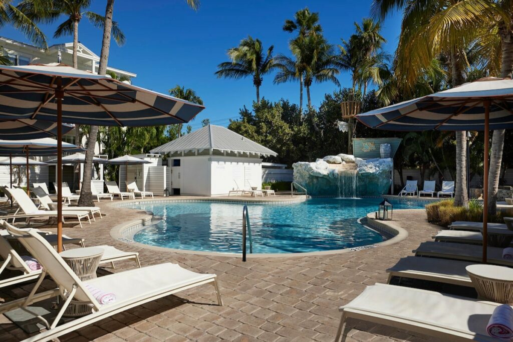 one of the pools featuring a waterfall and many umbrellas with pool chairs located at one of the best resorts in the Florida Keys!