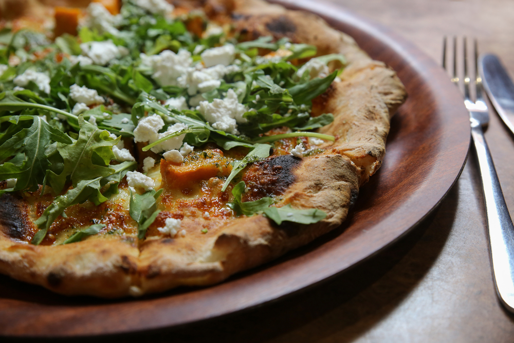 a pizza topped with arugula and goat cheese