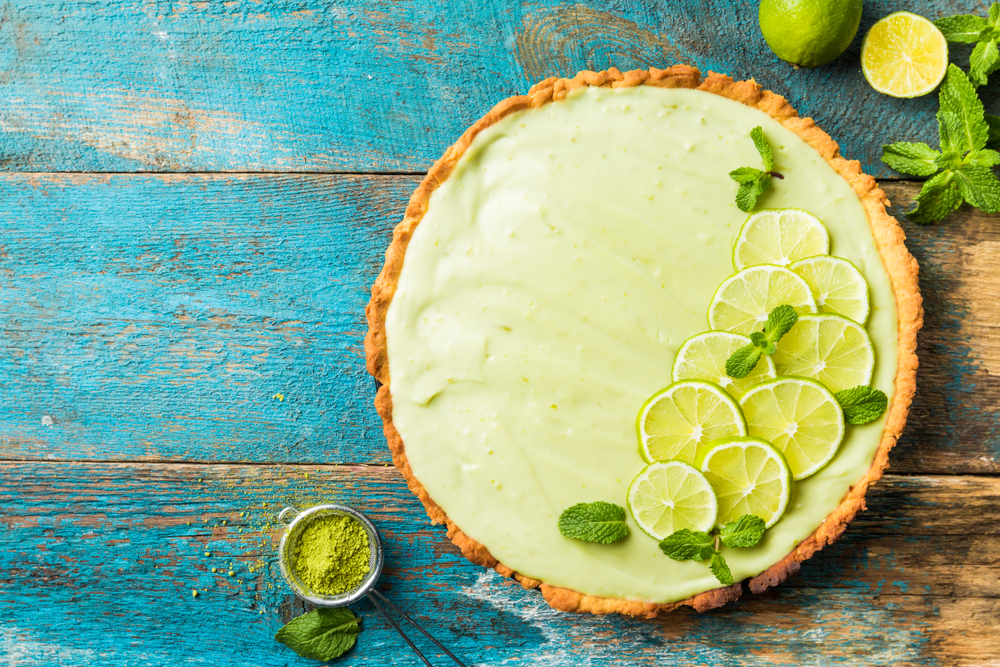 rustic teal blue wood picnic table topped with a beautiful key lime pie decorated with fresh slices of limes!