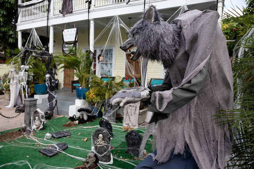 A house in the Keys decorated in Halloween decorations. There is a large wolf in the foreground and gravestones in the background. 