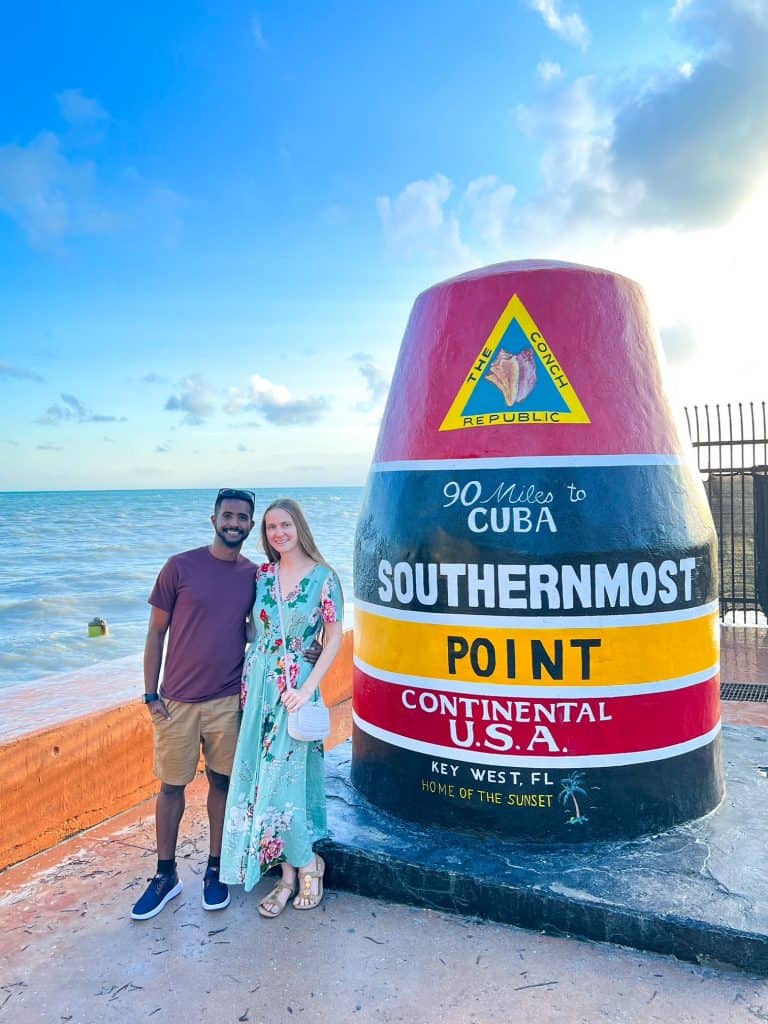 Couple standing in front of the southernmost point in Key West in an article about the  best time to visit the Florida Keys. 