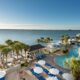 Where to stay in Florida if you want to be right on the beach, you can see a large pool, cabanas, palm trees, and the ocean at this hotel