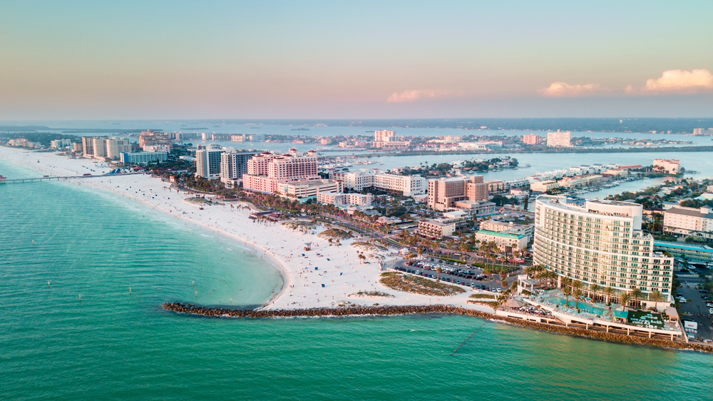 An aerial view of Clearwater Beach Florida as the sun is setting. You can see white sandy beaches and buildings on the coast