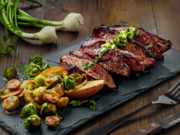 pan-seared steak with brussel sprouts served on a black board