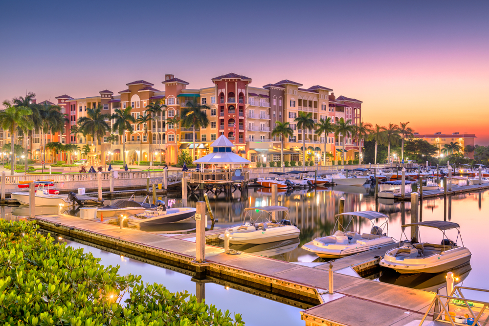 A dock in Naples Florida with a large hotel behind it at sunset
