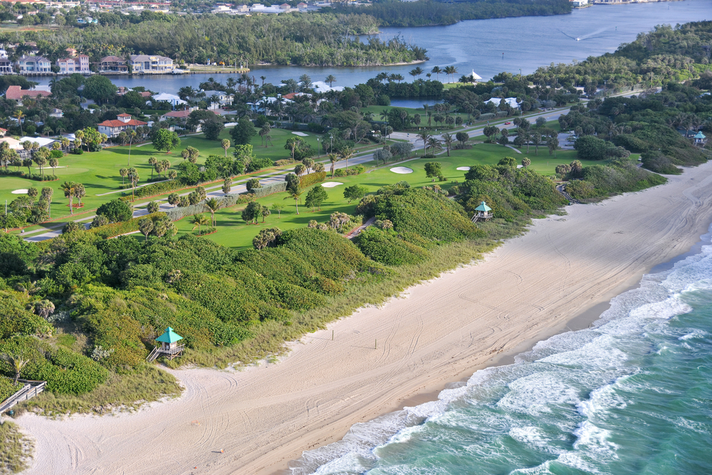 An aerial view of a sandy beach with a golf course behind it in Florida