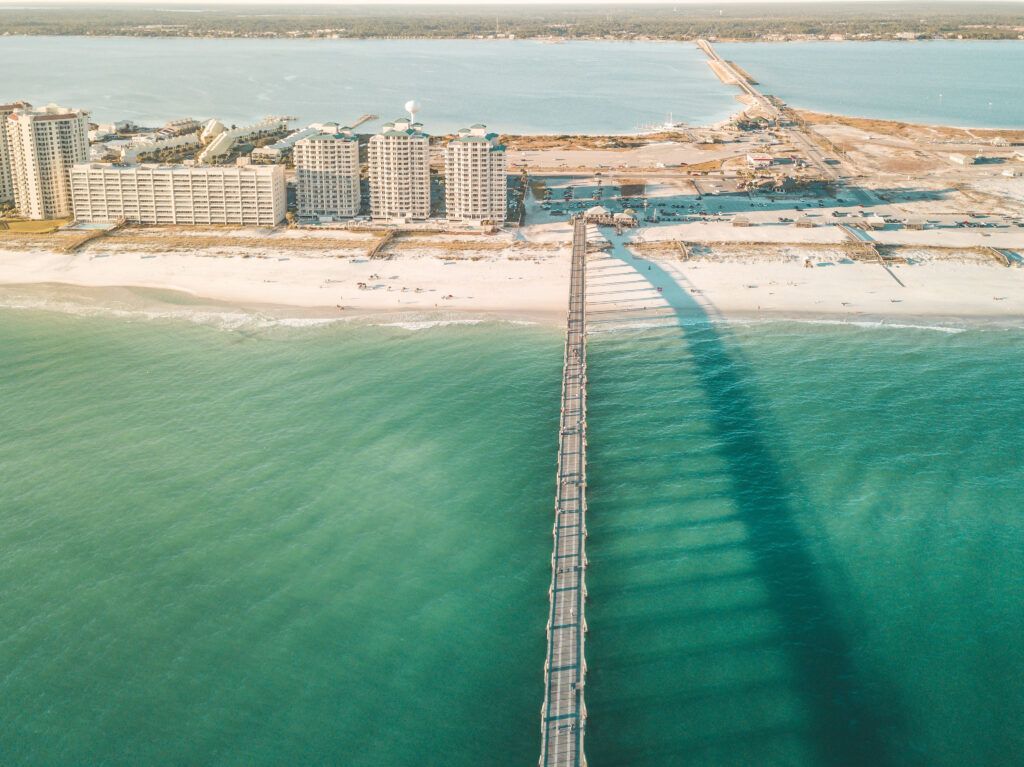nice beaches in North Florida show emerald green waters with a white sand shore and a long pier stretched over the water