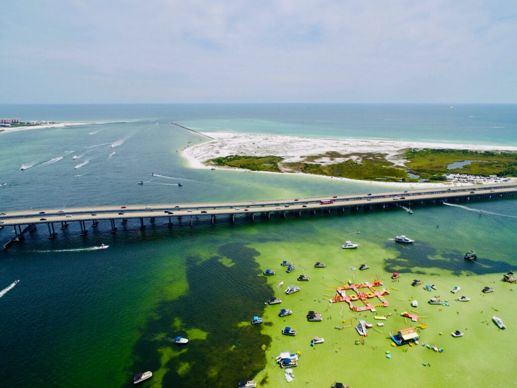 Clear green waters under long bridge with many boats crowded together