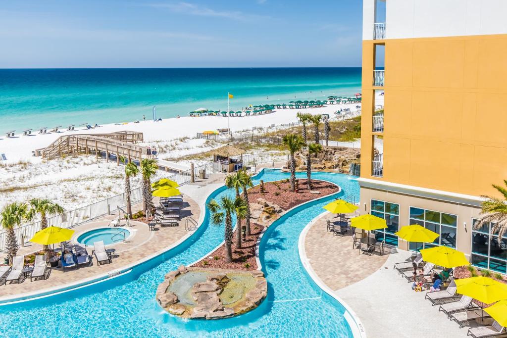 outdoor pool surrounded by yellow umbrellas and sunbeds overlooking the white sandy beach best beachfront hotels in destin
