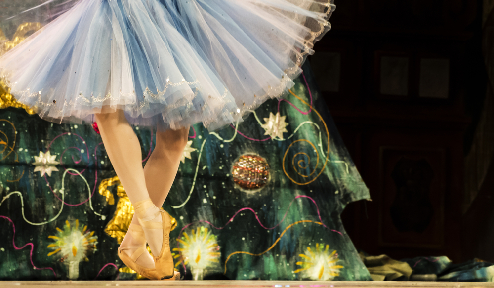 Close up of ballet dancer's feet with a Christmas tree in the background.