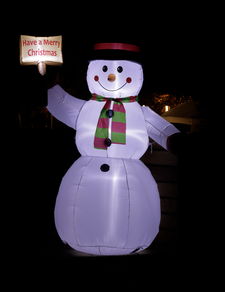 Lit, blow up snowman holding a merry Christmas sign.