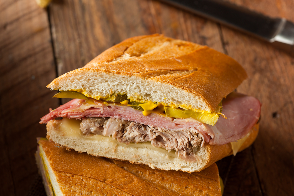 A yummy Cuban sandwich with ham, roast pork, cheese, mustard, and pickles.