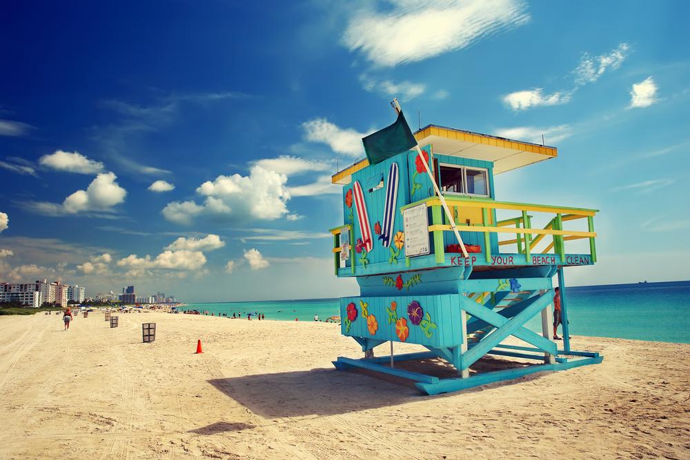 A brightly colored life guard stand with surfboards and flowers on it at the beach in Florida in February