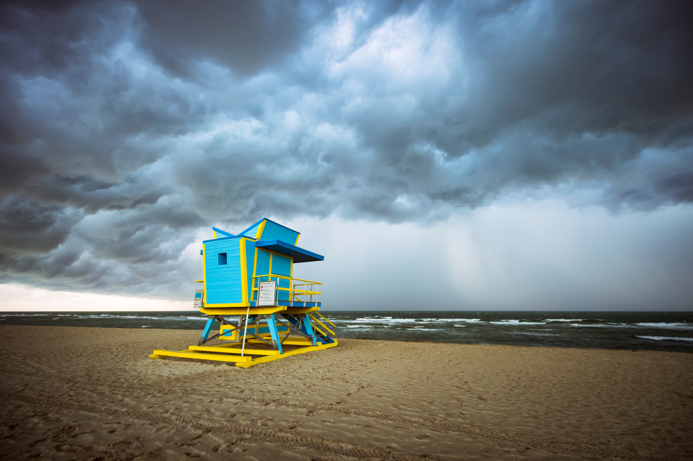 A blue and yellow lifeguard hut on a deserted beach in Florida in June as a storm comes to shore