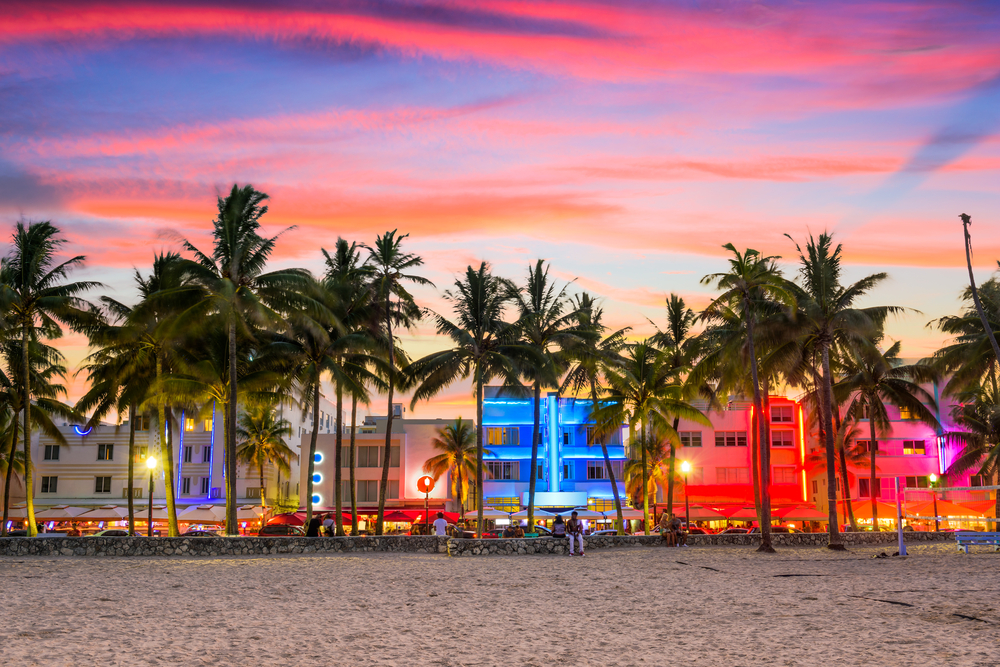 Miami Beach, Florida, USA on Ocean Drive at sunset. The buildings in the background are lit in different colors. 