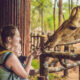A woman holding a baby and feeding a giraffe at the Miami Zoo one of the best things to do in Miami with kids