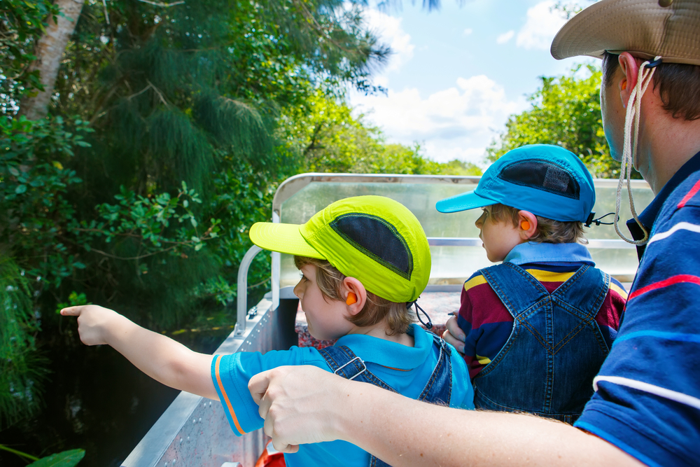 Kids point to the marsh on the side of a boat tour while parents experience Orlando with kids in an easy way! 