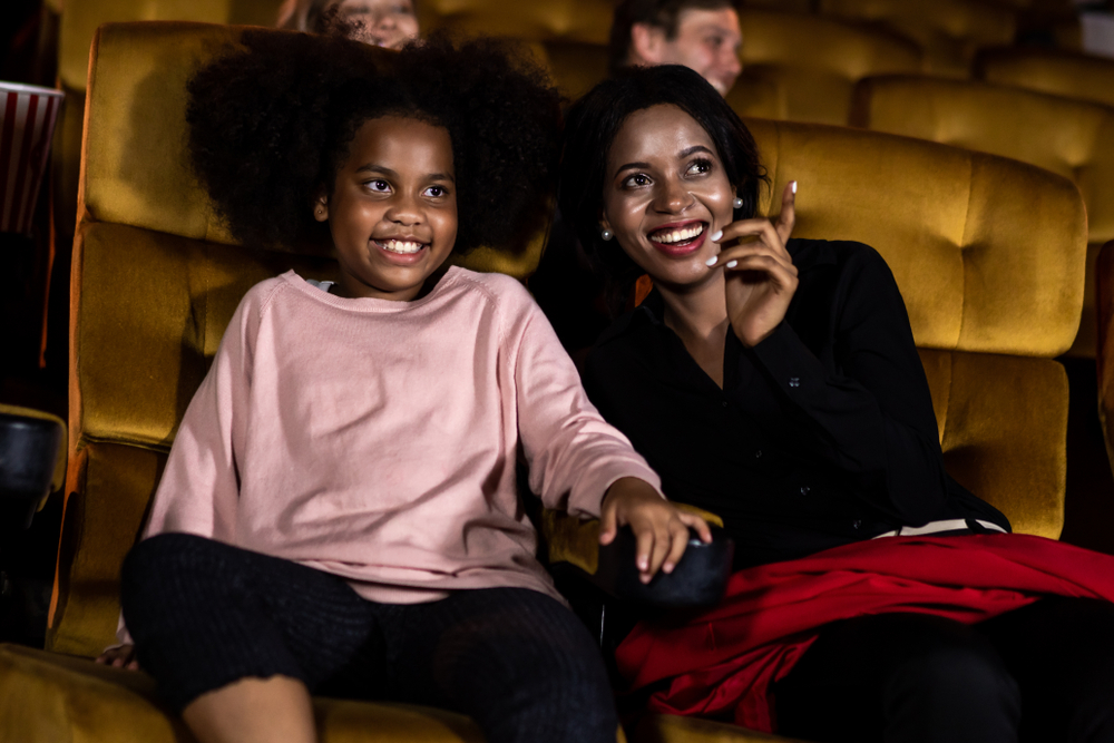 A woman leans over and talks to a child as they point toward a stage, admiring a show. There are tons of opportunities to see live entertainment, so Orlando with kids becomes easy in regards to seeing shows! 