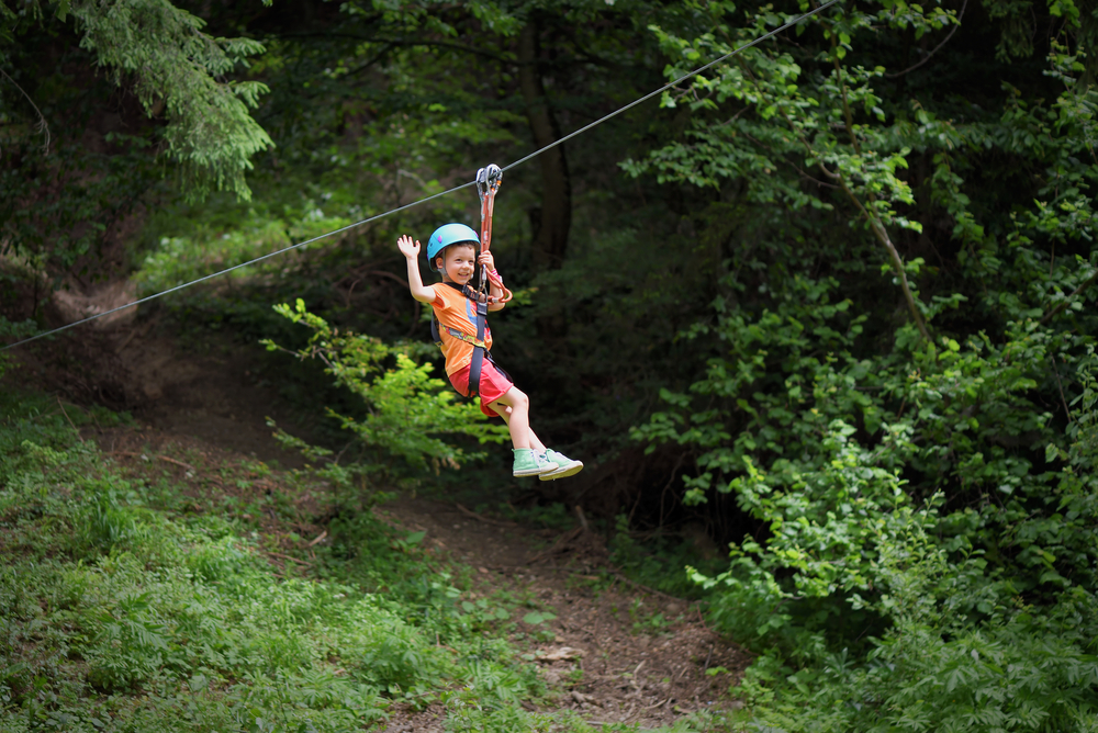 A child waves as he zips past a camera on a zip line. Gatorland gives kids and adults a chance to experience this adrenaline in Orlando! Of all things to do in Orlando with kids, this may be the most adrenaline inducing! 