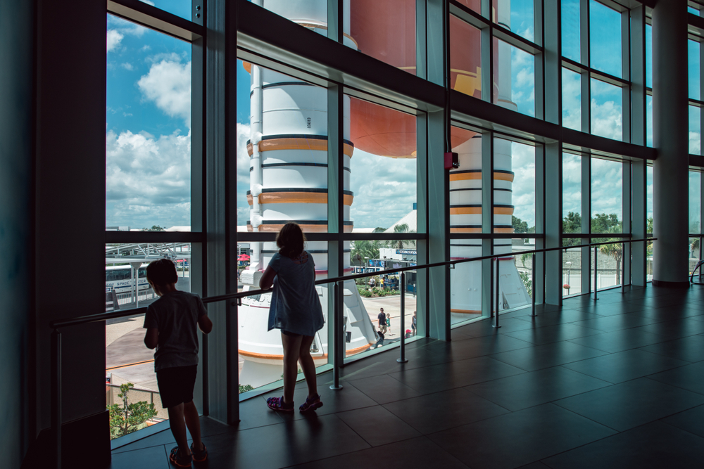 Two kids look out large windows at the space shuttles at Kennedy Space Center. Kennedy Space Center is already something to do in Orlando, but it is definitely something to do in Orlando with kids. 