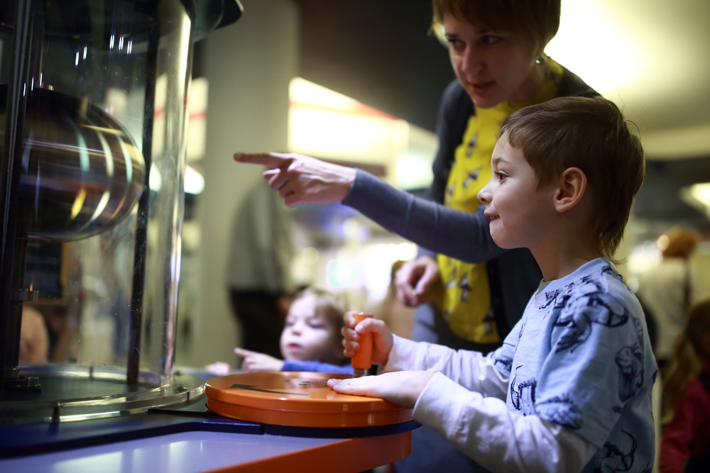 A mom points and directs a child through an interactive exhibit at Wonder Works, one of the top things to do in Orlando with kids. 