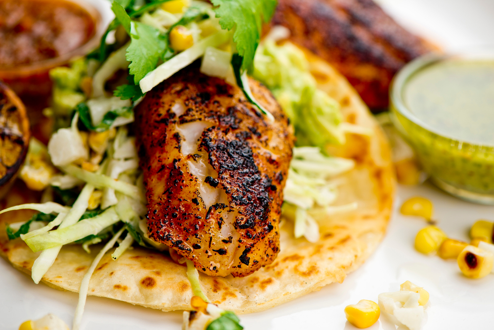 A close up of a grilled fish taco with corn and avocado, like that one served at Captain & Krewe, one of the best seafood restaurants in Naples.