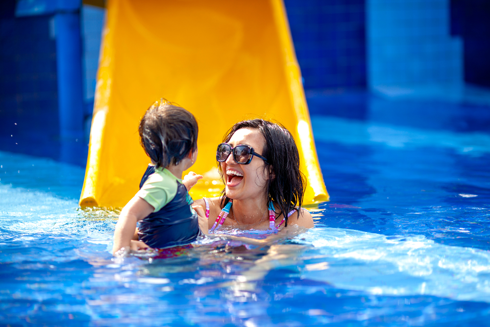 Mother and child in the water by a water slide. Visiting the waterpark is one of the things to do in Tampa with kids. 