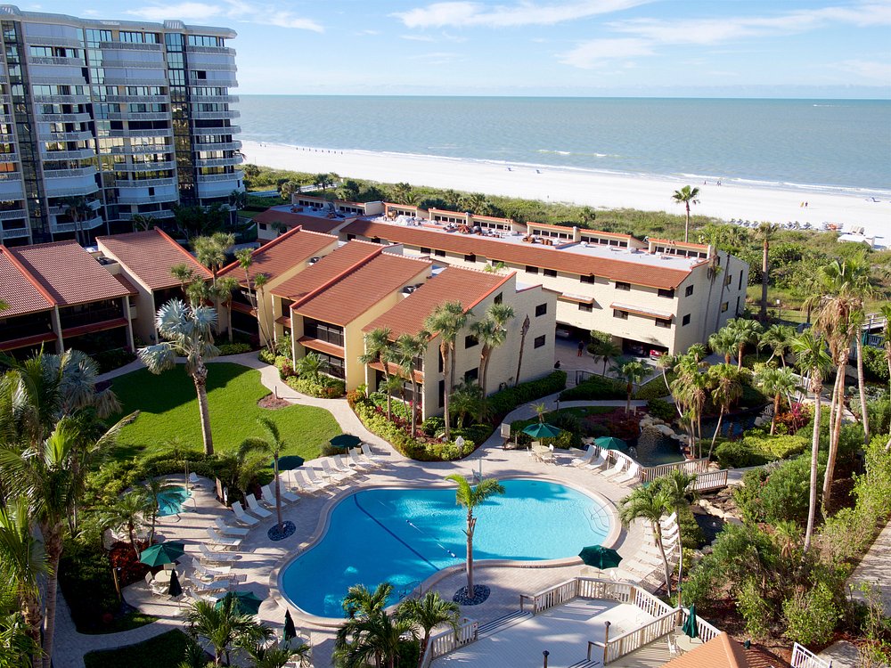 Aerial view of condos around a swimming pool located beside the beach