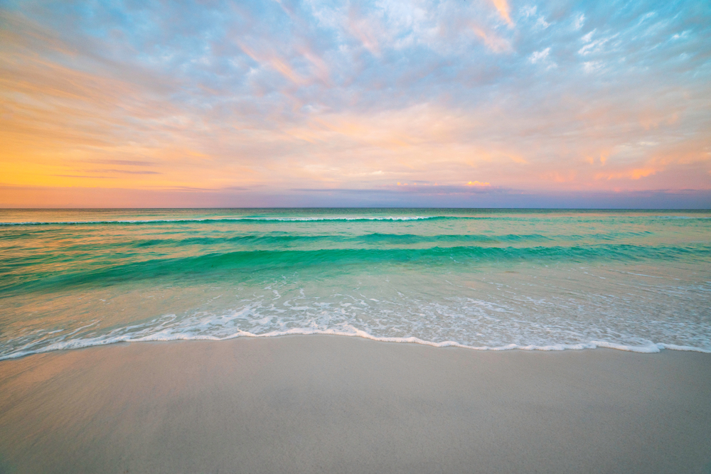 Turquoise ocean waves against a yellow and purple sky at sunrise, when things are most humid in Florida in November.