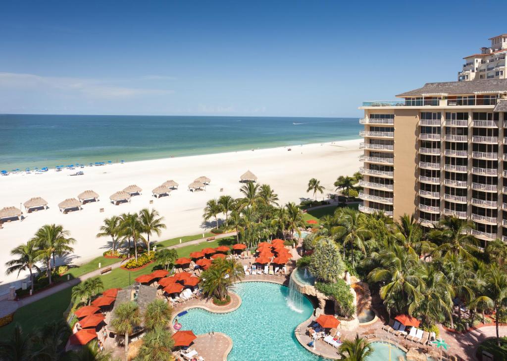 Outdoor swimming pool beside the beach surrounded by palm trees and hotel tower best beach resorts on Marco island