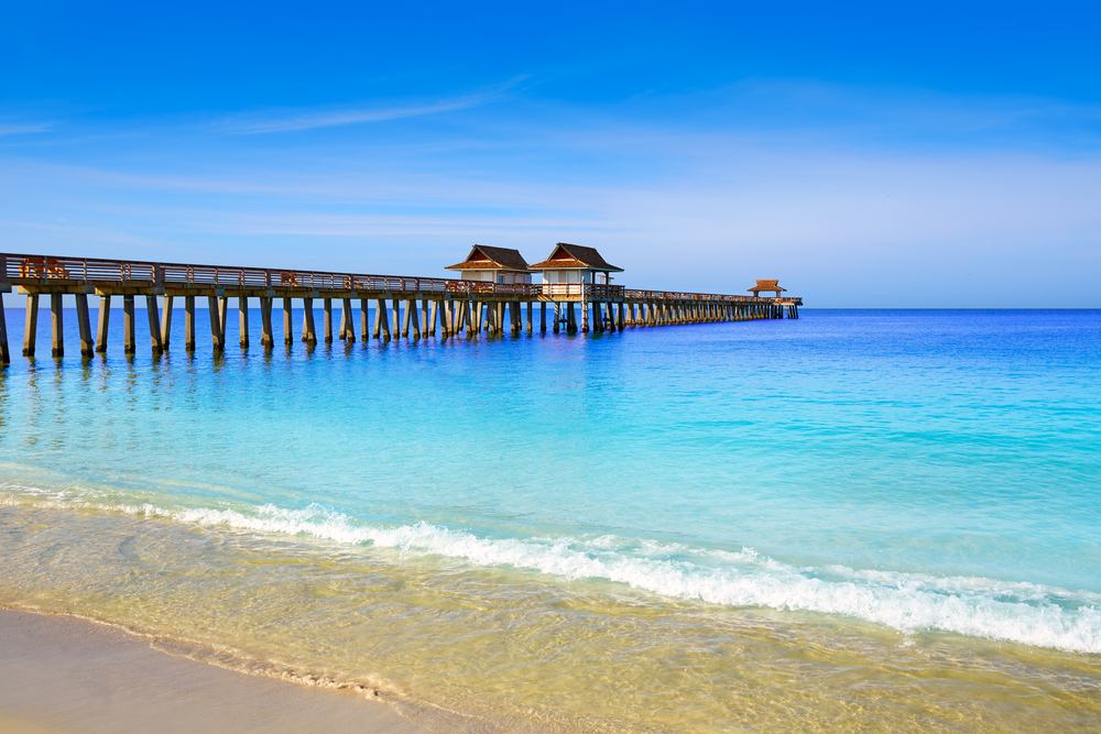 Naples Pier at the beach over bright, blue water.
