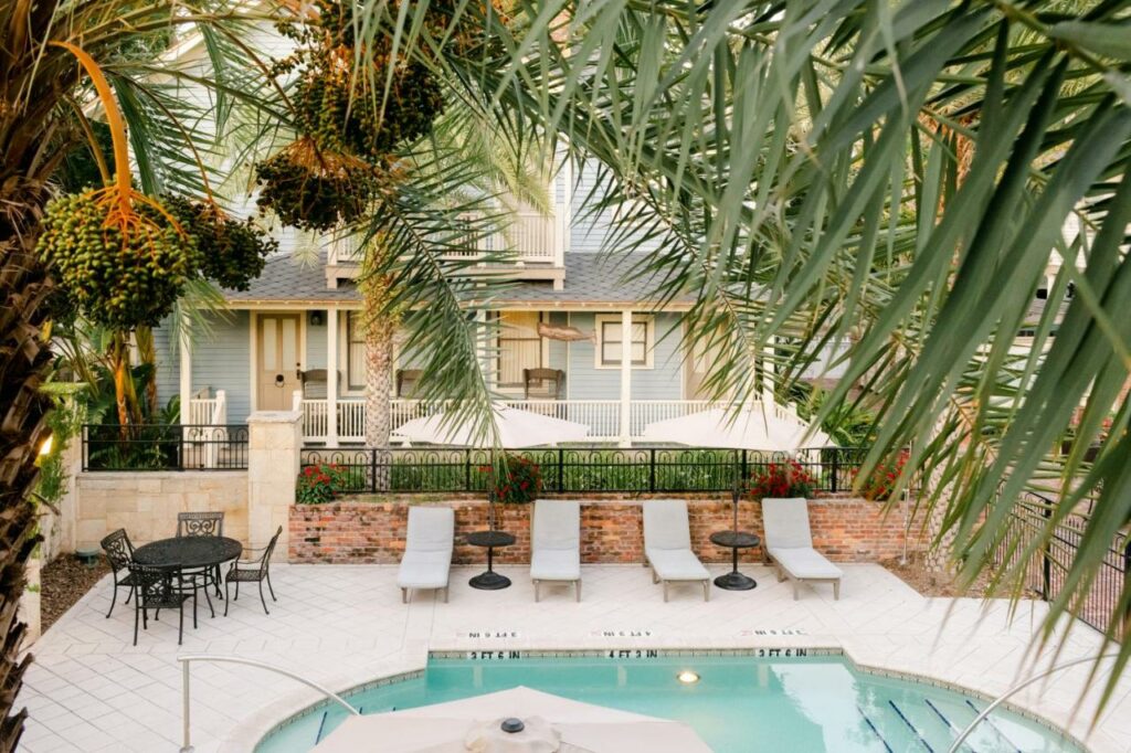 the pool from one of the room with lounge chairs and palm trees and loungers and umbrellas