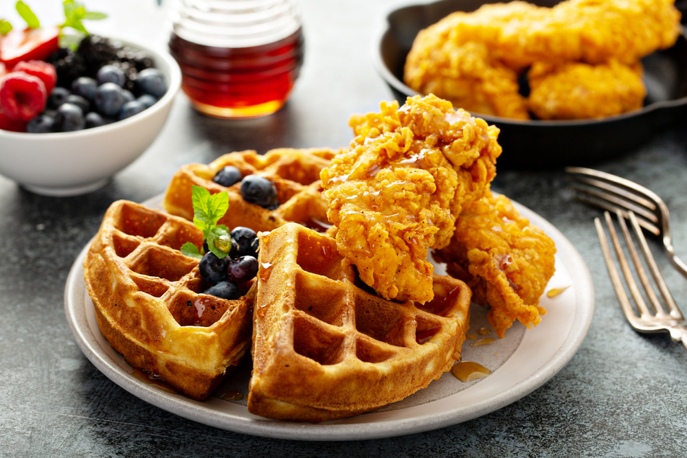Waffles with fried chicken and maple syrup, southern comfort food. The article is about brunch in Miami