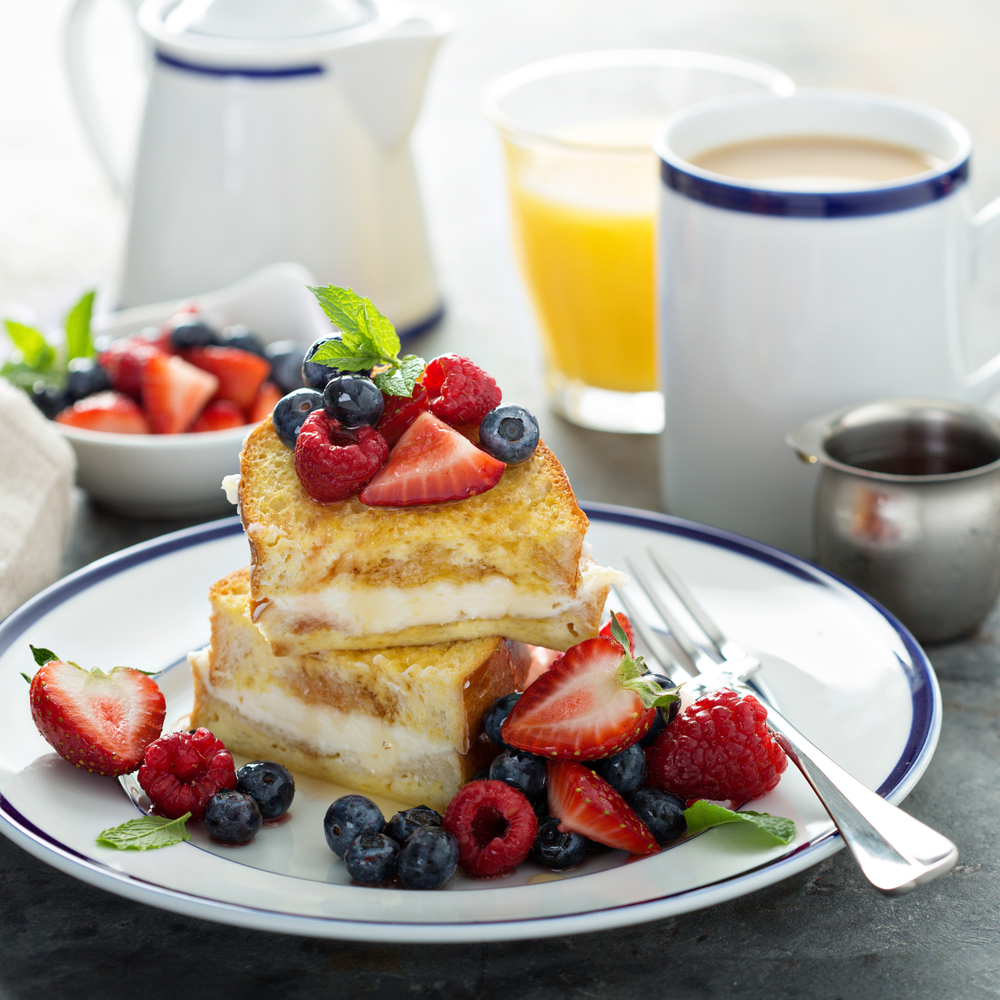 Baked french toast with cream cheese filling topped with berries. The article is about brunch in Miami