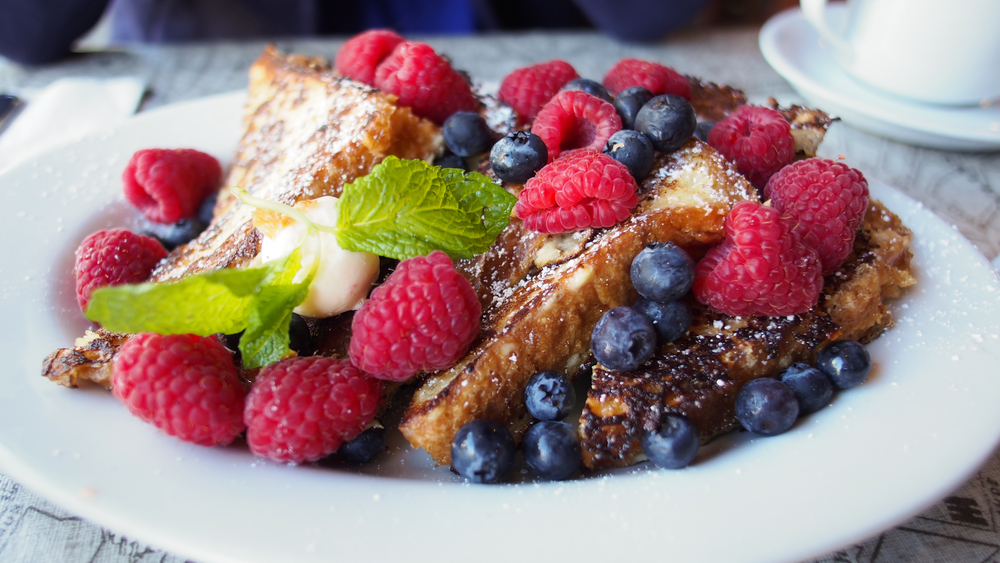 french toast topped with fresh berries and powdered sugar 