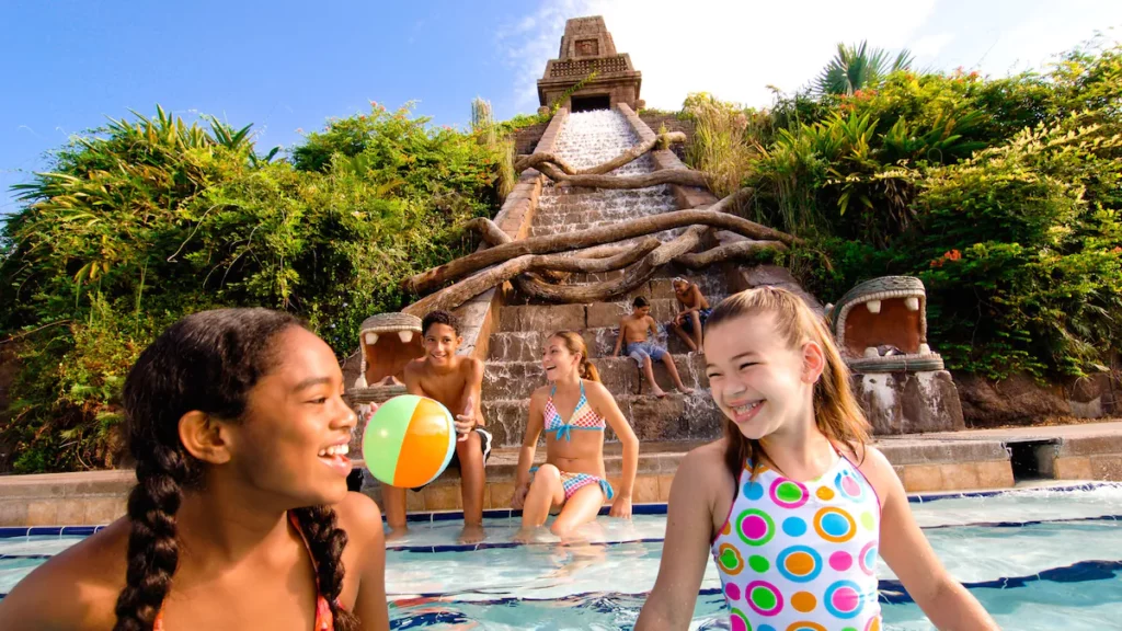 Kids sit at the base of a waterfall that is shaped like a pyramid at Disney's Coronado Springs which is one of the  best waterpark hotels in Orlando. 