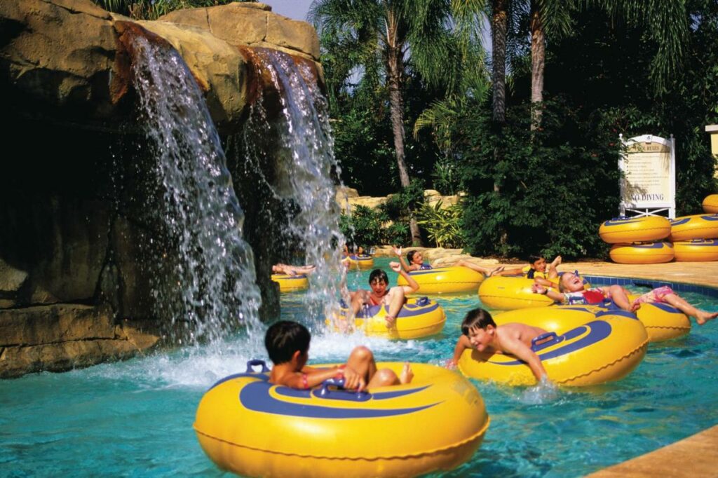 Kids sit in yellow tubes as they float through a lazy river with waterfalls at  one of the best waterpark hotels in Orlando.