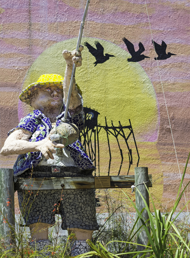 A mosaic-covered statue of a fisherman stands outside one of the art galleries in Cedar Key, which are some of the best things to do in Cedar Key.