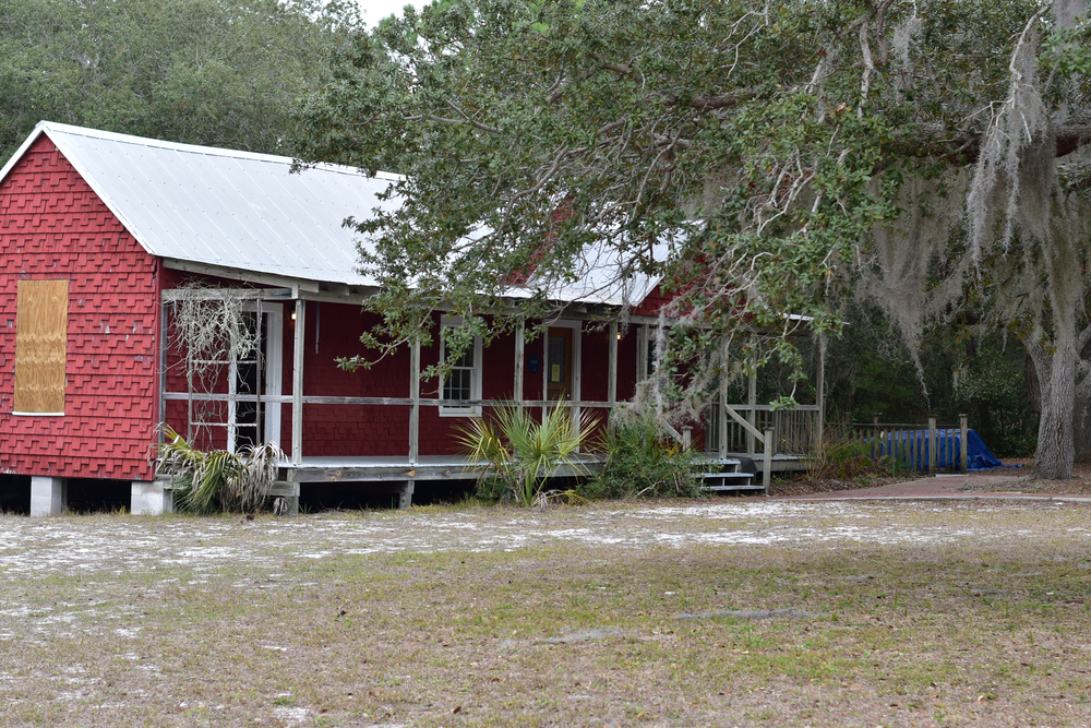 A red and white cabin sits on the grounds of Cedar Key State Park, where visiting the museum is one of the best things to do in Cedar Key, FL.