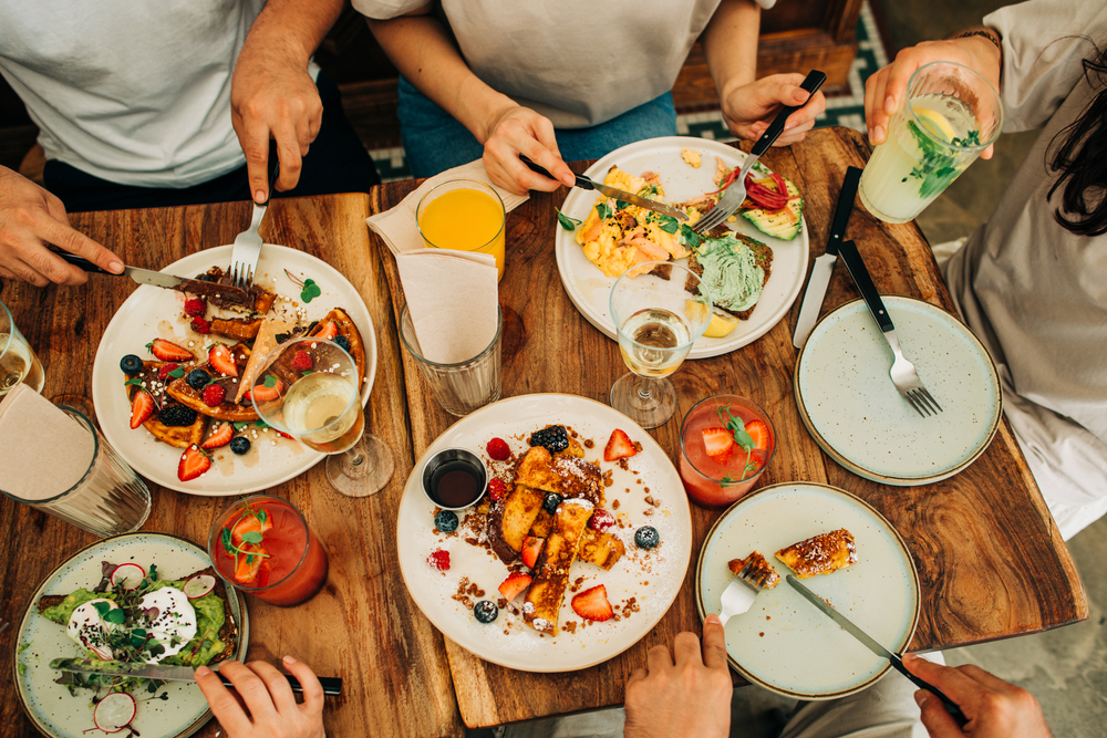 friends at a table enjoying brunch in orlando with favorite drinks, eggs, french toast, and avocado toast