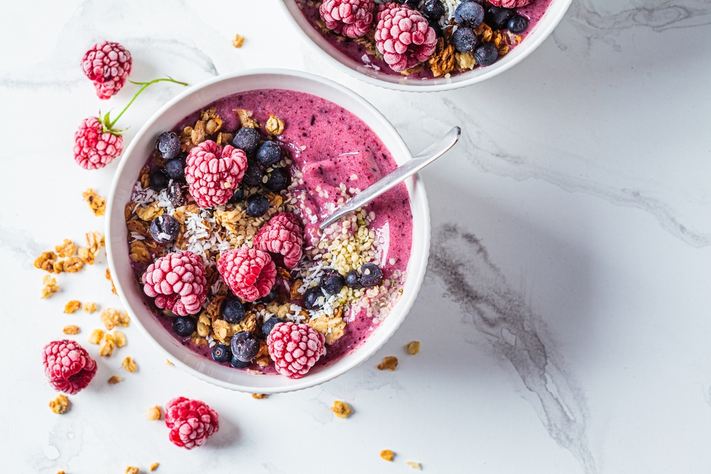 A white bowl filled with raspberries, blueberries and oats.