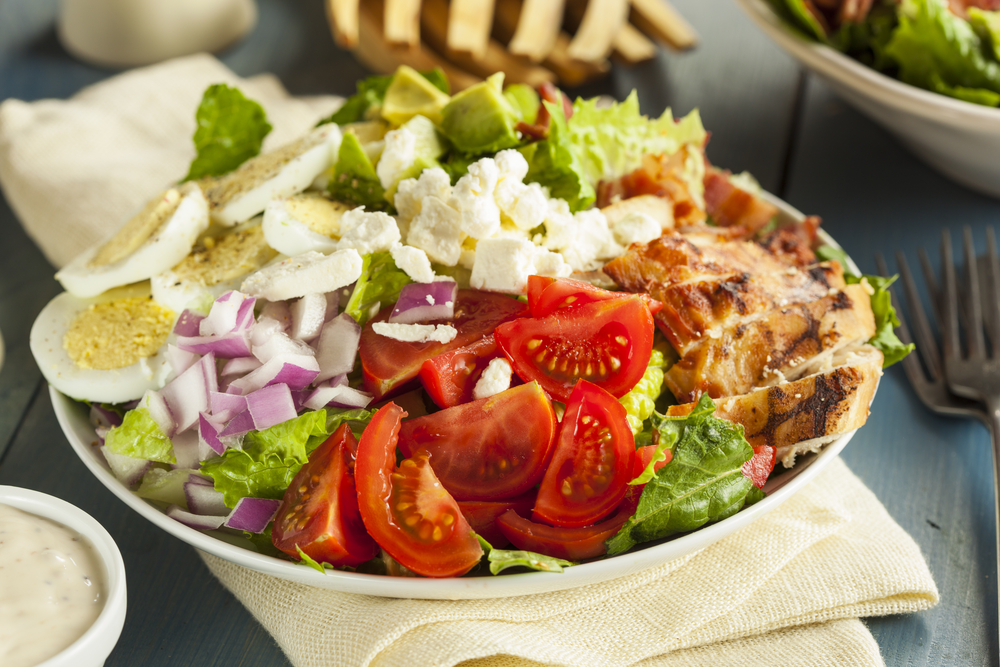 A Cobb salad piled high with vegetables, tomatoes, eggs, and chicken.