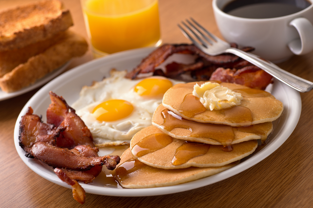 Plate with a classic breakfast of pancakes, eggs, and bacon.