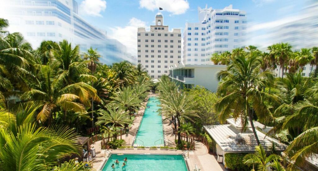 A long, T-shaped swimming pool surrounded by palm trees at the National hotel, one of the best places to stay in Miami for adults.