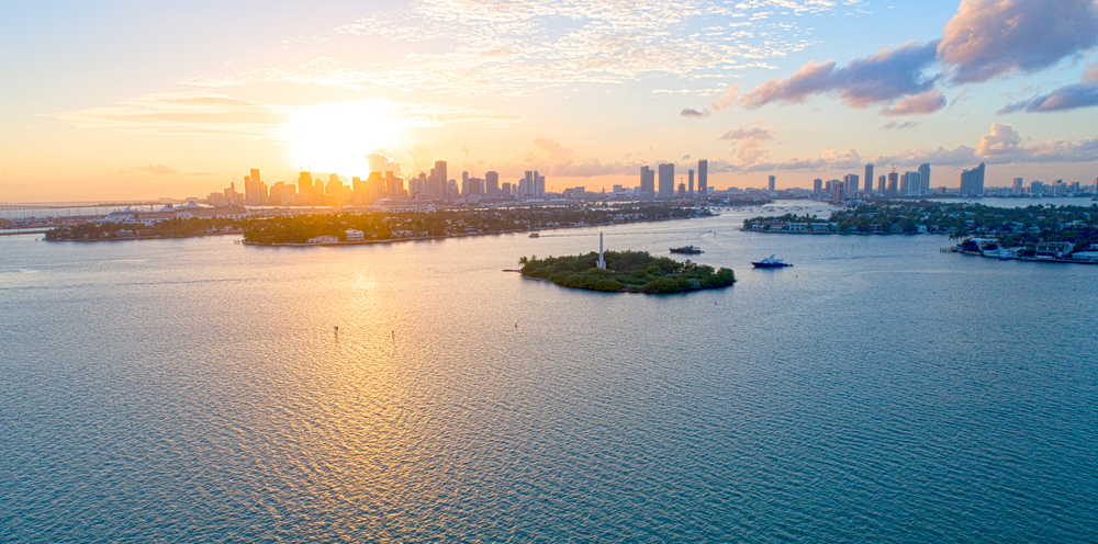 A golden and purple sunset over Miami, as seen from above on a mostly-clear day.