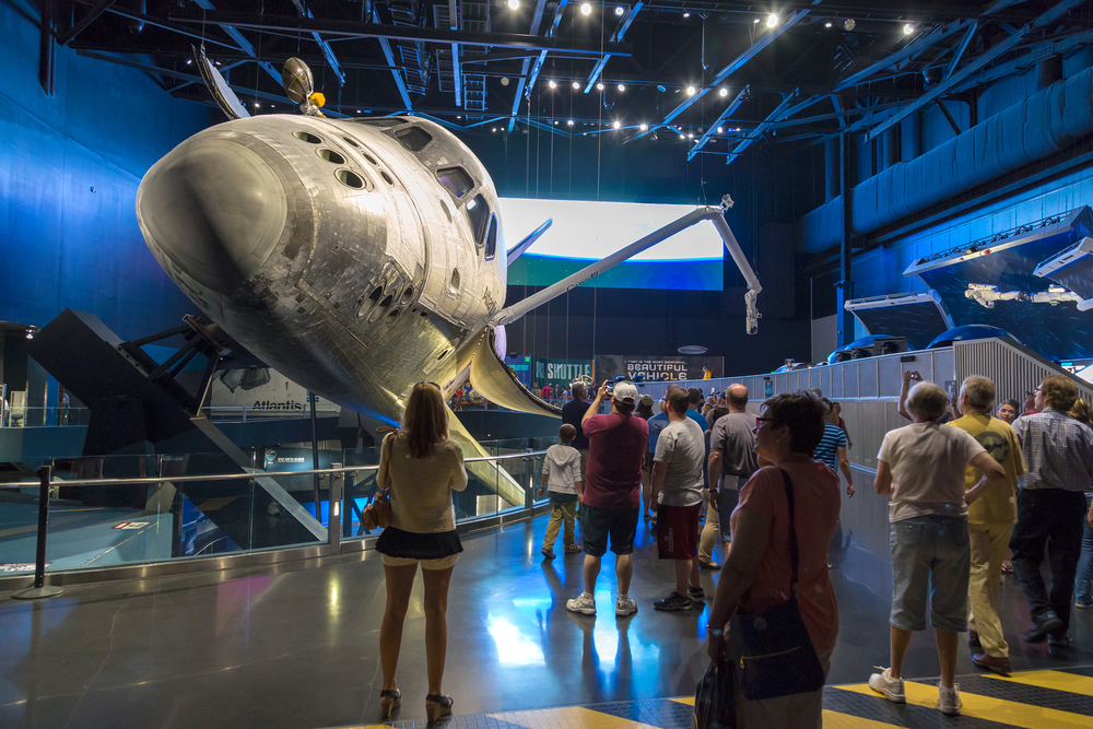 Guests gather around a space craft, all admiring it's big nose and wide windows at the Kennedy Space Center, which is a perfect adventure for Orlando for adults.