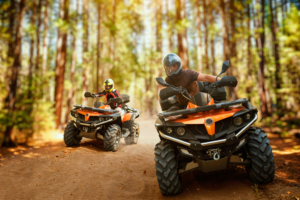 Two adults on orange ATV bikes take a turn on the trails of Florida: these tours are perfect in Orlando for adults! 