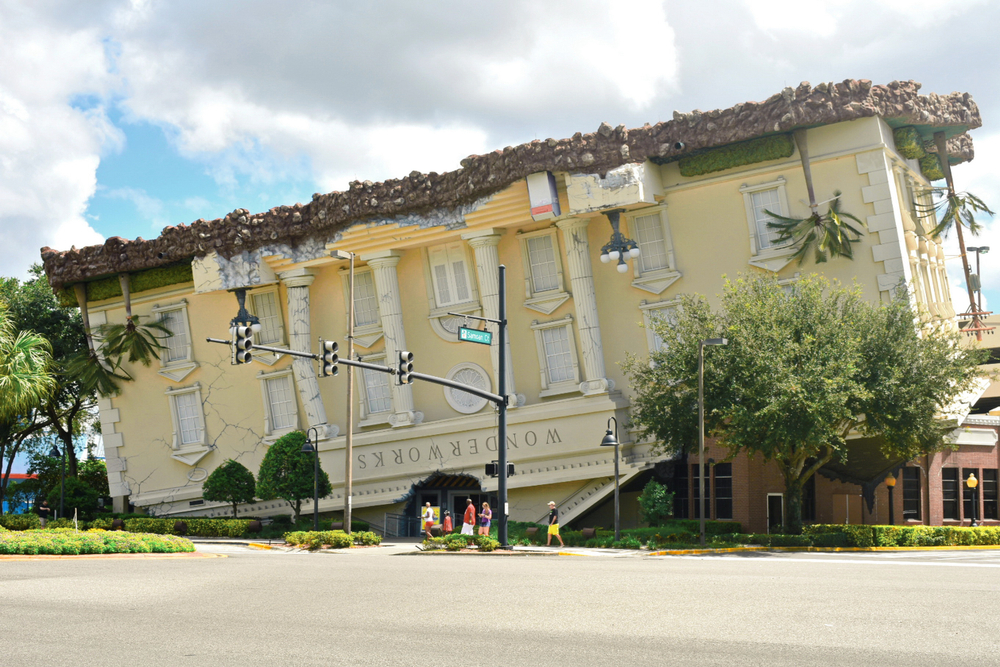 Upside amazing building Wonderworks in International Drive. People are stood outide the building and there is a road in front of it. 