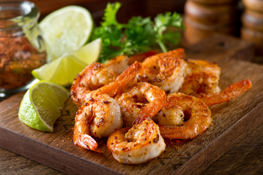 A series of seasoned shrimp are sitting on a wooden block with lime on the side to enhance the flavor at one of the best restaurants in Siesta Key Fl